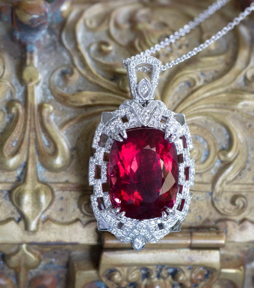 Welcome to true, luxury jewelry.  This is perhaps our most extravagant handcrafted piece to date, featuring a natural cushion shaped rubellite tourmaline from Brazil.  The stone has a red hue with hints of peachy pink depending on the viewing angle.  The stone is untreated and weighs 21.02ct.  We've set it securely with double claw prongs in a diamond-rich Art Deco inspired setting.  The pendant features just under a carat of F/G color, VS2 clarity full cut diamonds, highlighted with layers of piercing and 